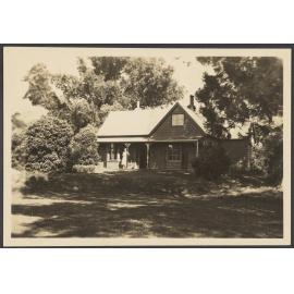 House among trees with woman on verandah