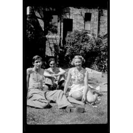 Three people sitting on grass