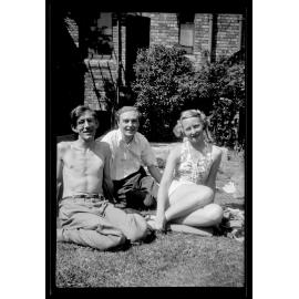 Three people sitting on grass