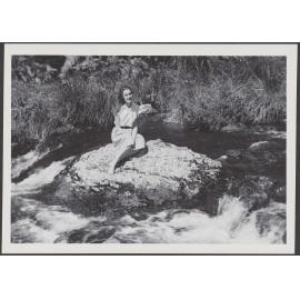 [? Garland] sitting on a rock in a river