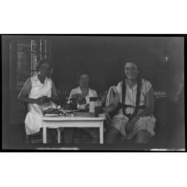 Three women with food and drink at a small table