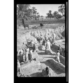 People excavating a deep area of palace archaeological site