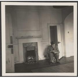 Man sitting by fireplace reading