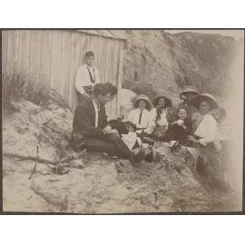 Family picnic on the beach next to a wooden shed