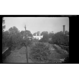 View over garden towards building and tall chimney