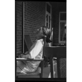 Woman sitting on the vernadah at Manono, with her head back and eyes closed