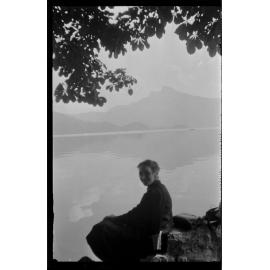 Woman sitting on a shore, with a mountain in the distance