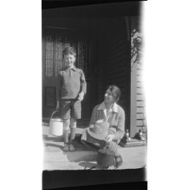 Boy and woman on a doorstep, carrying billies