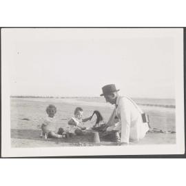 Unknown man and two children playing on a beach