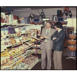 Two men standing next to a Cadbury display stand