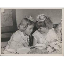 Two young girls with party hats and food