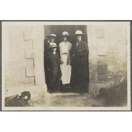Four unidentified people standing in doorway of building