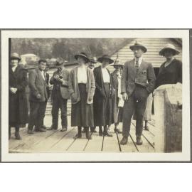 Eleven unidentified people on wooden deck, standing in front of a wooden building