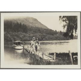 Charles [and Lesley] Brasch standing in front of boats on pier