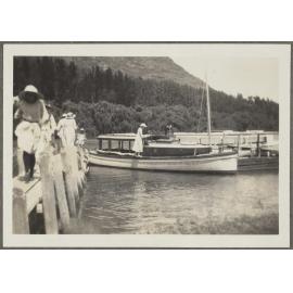 Unidentified girl standing on a boat and five unidentified people walking up pier