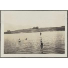 Four unidentified children standing in lake