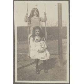Lesley Brasch sitting on swing, with unidentified girl