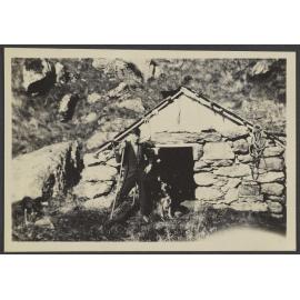 Man standing in front of stone hut