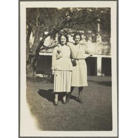 Two unidentified women standing on lawn outside house