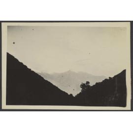 Snow capped mountains through two large hills