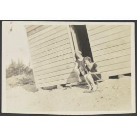 Two unidentified women sitting on step of wooden shack