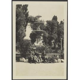 Henry, Charles and [Lesley] Brasch sitting in front of a water fountain