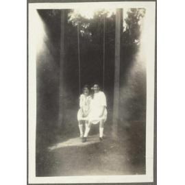 Lesley Brasch and unidentified girl sitting on swing