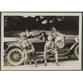Henry Brasch sitting outside car, with two unidentified people