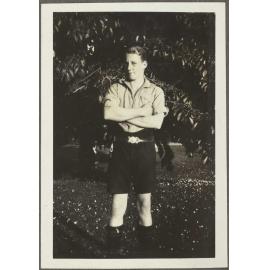 Boy standing cross-armed in front of a tree