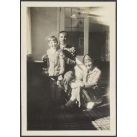 Unidentified boy standing next to an unidentified man and woman