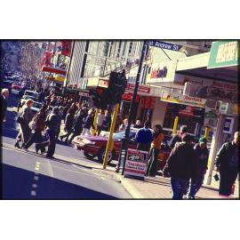 George Street, Dunedin, with pedestrians, vehicle traffic, and shops
