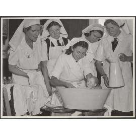 Nurse and students [?] bathing baby doll