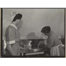 Nurse and mother [?] bathing baby