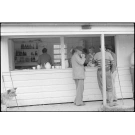 Women working in a canteen and men outside