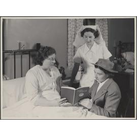 Two nurses and a mother reading "Modern Mothercraft"