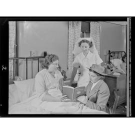 Two nurses and a mother reading "Modern Mothercraft"