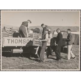 Five men unloading crates from the back of a Thomsons truck