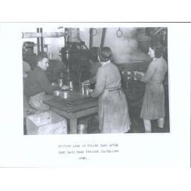 Putting lids on filled cans after they have been through the travelling oven