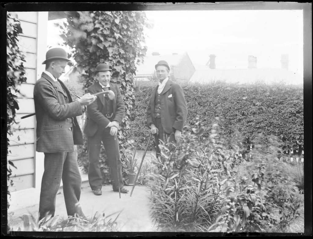Jim Manson (centre) and two unidentified men in a garden, next to a house